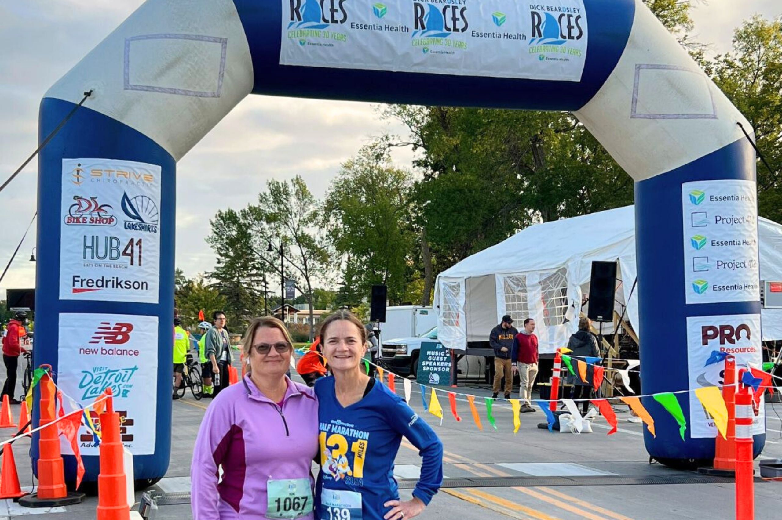 two happy female racers in front of finish line arches